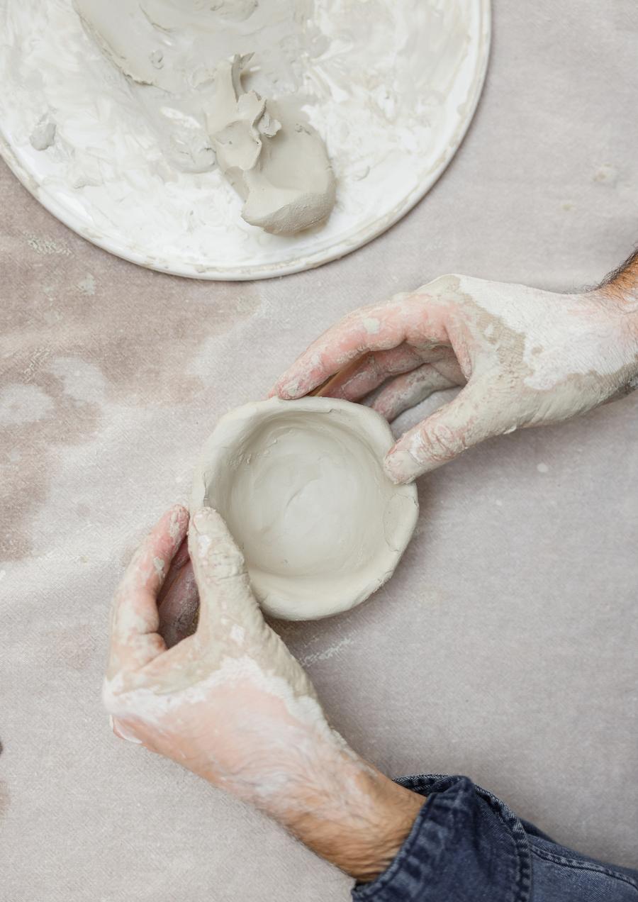 Hands shaping a small clay bowl